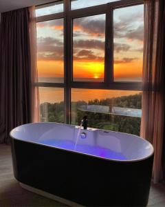 a bath tub in front of a window with a sunset at Residence Sky in Sochi