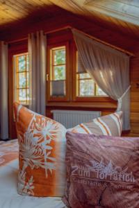 um quarto com uma cama com almofadas e janelas em Gaststätte und Pension Zum Torfstich em Hundshübel
