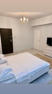 a bedroom with a large white bed and a chandelier at Studio Katerina in Mamaia