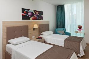a hotel room with two beds and a chair at The Room Hotel & Apartments in Antalya