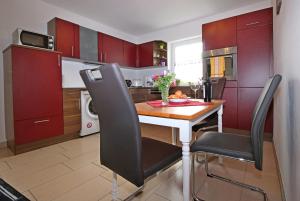 a kitchen with red cabinets and a wooden table and chairs at Ferienwohnung Wandl in Bad Griesbach