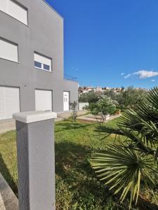 a white building with a palm tree in front of it at Casa llena in Seget Vranjica