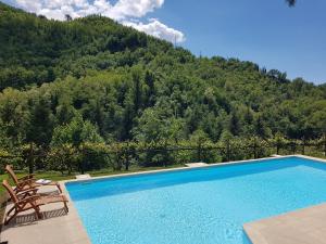 a swimming pool with two chairs and a mountain at Il Bosco di Campo Marzano green & sky in Borzonasca