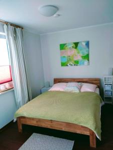 een slaapkamer met een bed met een groene deken en een raam bij Meerzeit 1 Graal-Müritz in Graal-Müritz