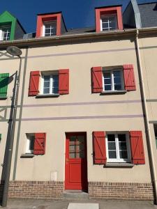 a white building with red shutters and a red door at L'Avocette en Baie in Saint-Valery-sur-Somme
