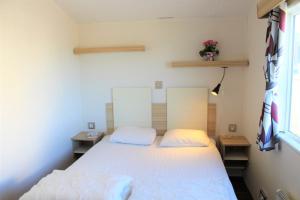 a bedroom with a bed and two tables and a window at Visingsö Villavagnar in Visingsö