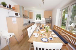 a kitchen with a long wooden table with chairs at Ferienhaus II Wiesenblick in Grömitz