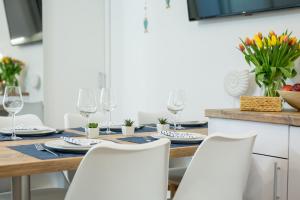 a dining room table with white chairs and wine glasses at Apartament 9B Blue Marine Poddąbie in Poddąbie