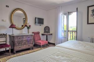 - une chambre avec un lit, une commode et un miroir dans l'établissement Hotel Museo Los Infantes, à Santillana del Mar