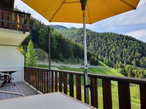 a balcony with a table and an umbrella at Hotel Zarera in Poschiavo
