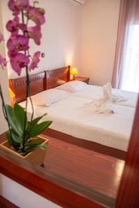 ペルディカにあるMokos Roomsのベッドルーム1室(ベッド1台付)、紫の花の花瓶1枚