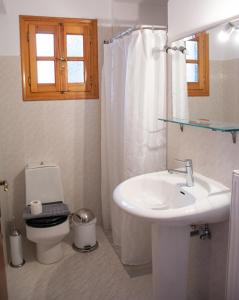 a white bathroom with a sink and a toilet at Mokos Rooms in Perdika