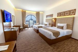 Hamdan Plaza Hotel Salalah, an HTG Hotel في صلالة: غرفة فندقية بسريرين ونافذة كبيرة