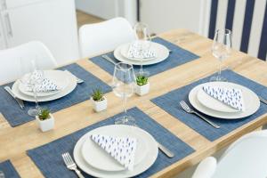 a wooden table with plates and wine glasses on it at Apartament 19B Blue Marine Poddąbie in Poddąbie