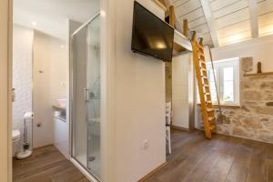 ein Bad mit Dusche und ein TV an der Wand in der Unterkunft Romantic Apartment in Center in Split