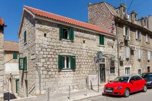 ein rotes Auto, das vor einem Steingebäude parkt in der Unterkunft Romantic Apartment in Center in Split
