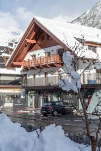 索爾登的住宿－Lutonia Appartements Sölden，一座有雪盖的建筑,前面有一辆汽车停放