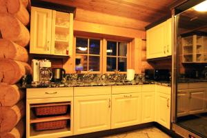 a kitchen with white cabinets and a wooden wall at Excellent log house with a sauna in Lahemaa! in Hara