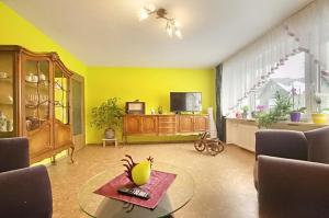 a yellow living room with a table and a tv at Haus Lila Welle in Nordhalben