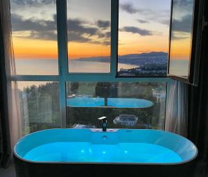 a bathroom with a blue tub in front of a window at Residence Sky in Sochi