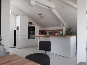 a kitchen with white cabinets and a black chair at appartcathedrale in Écrouves