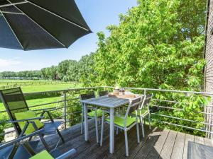 una terraza con mesa, sillas y sombrilla en Cushy Apartment with Private Terrace Heating en Maldegem