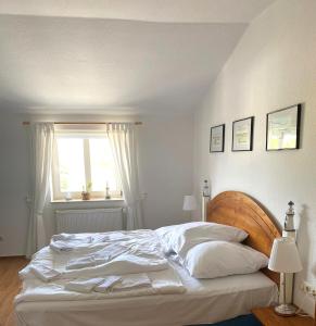 a bedroom with a bed with white sheets and a window at Meerblick Apartment in Göhren