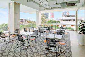 a restaurant with tables and chairs and a large window at HARRIS Hotel & Conventions Bundaran Satelit Surabaya in Surabaya