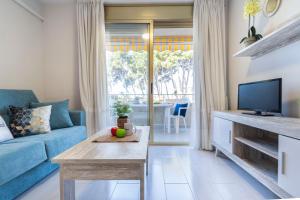 a living room with a blue couch and a tv at Apartamentos Internacional Arysal in Cambrils