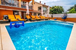 una piscina en un hotel con sillas anaranjadas y azules en House Andja with Pool, en Banjole