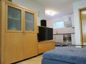 een woonkamer met een grote houten kast en een flatscreen-tv bij Ferienwohnung Emilia in Münsingen