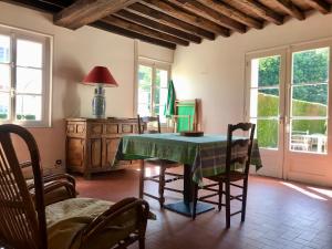 a dining room with a table and chairs and windows at Gite de Mauxe in Acquigny