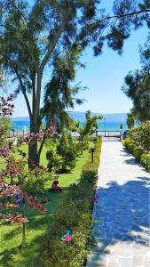a walkway in a park with trees and flowers at Amarynthos Beachfront Vacation House with garden in Áno Váthia