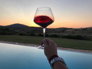 a person holding up a glass of wine at sunset at Macchiabuia in Capalbio