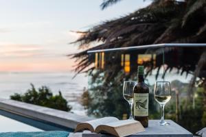 uma garrafa de vinho e dois copos numa mesa com um livro em Living Hotel Lion's Eye na Cidade do Cabo