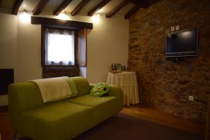 a living room with a green couch and a television at Casa do Neveiro in Góis