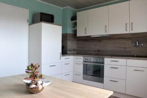 une cuisine avec des placards blancs et une table avec une plante dans l'établissement Ferienhaus zur schönen Aussicht, à Hardt