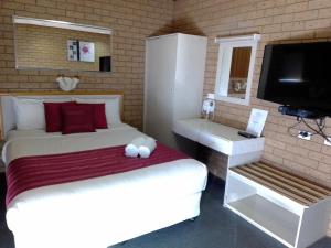 um quarto com uma cama e uma televisão de ecrã plano em Country Home Motor Inn em Shepparton