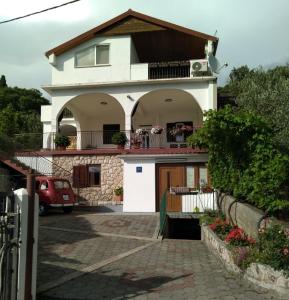 a house with a car parked in front of it at Apartman Larus in Starigrad-Paklenica
