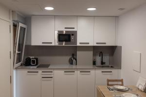 cocina con armarios blancos y microondas en Loft en Zarauz con parking Hator 1, en Zarautz