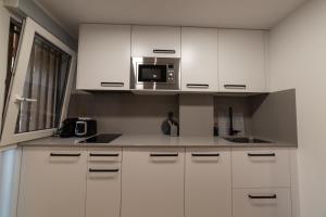 cocina con armarios blancos y microondas en Loft en Zarauz con parking Hator 1, en Zarautz