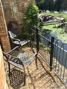 two chairs sitting on a fence next to a body of water at River Courtyard Apartment In The Heart Of Stneots in Saint Neots