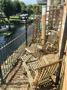 two wooden chairs sitting next to a fence next to a river at River Courtyard Apartment In The Heart Of Stneots in Saint Neots