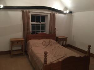a bedroom with a wooden bed with two tables and a window at The Old Rose And Crown - St Neots in Saint Neots