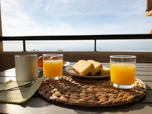 una mesa con una bandeja de comida y dos vasos de zumo de naranja en Lovely seaside apartment in front of Calafell beach and Cunit beach, en Segur de Calafell