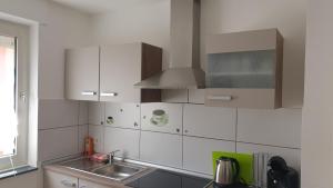 a kitchen with white cabinets and a sink at Ferienwohnung Biewer in Trier