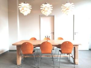 a dining room table with orange chairs and chandeliers at berlincity in Berlin