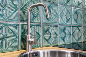 a sink in a kitchen with a green tiled wall at Relaks Apartamenty in Kraków +117 photos