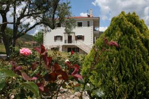a white house behind a garden with flowers at Venetiko Villas in Nafpaktos