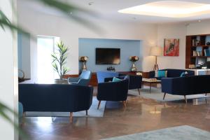 a living room with blue chairs and a table at OPOHOTEL Porto Aeroporto in Maia